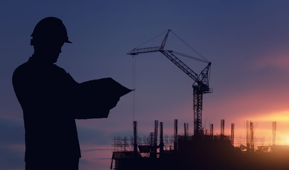 Silhouette engineer standing survey work on construction over blurred Worker in construction site and sunset. Silhouette engineer standing survey work on construction over blurred Worker in construction site and sunset.