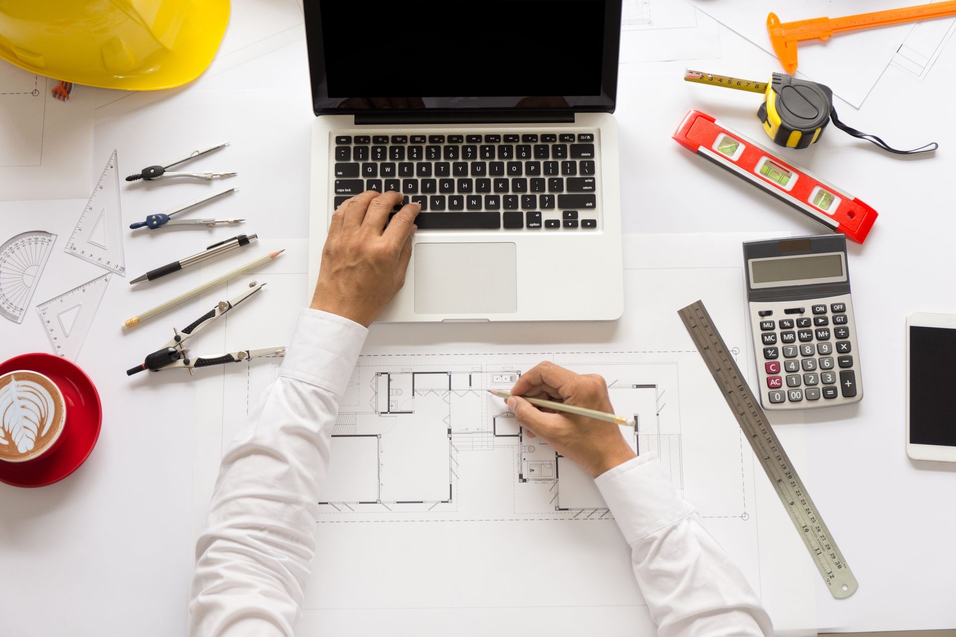 Top view, Architect or engineer hands working on blueprint plans with a pencil, a ruler, calculator, smartphone, laptop and engineering tools. Architect or engineer working on blueprint in office. Top view, Architect or engineer hands working on blueprint plans with a pencil, a ruler, calculator, smartphone, laptop and engineering tools. Architect or engineer working on blueprint in office.